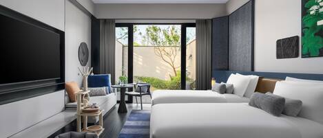A modern hotel room with a large bed, a sofa, a TV, a small table, and a view of the outdoors.