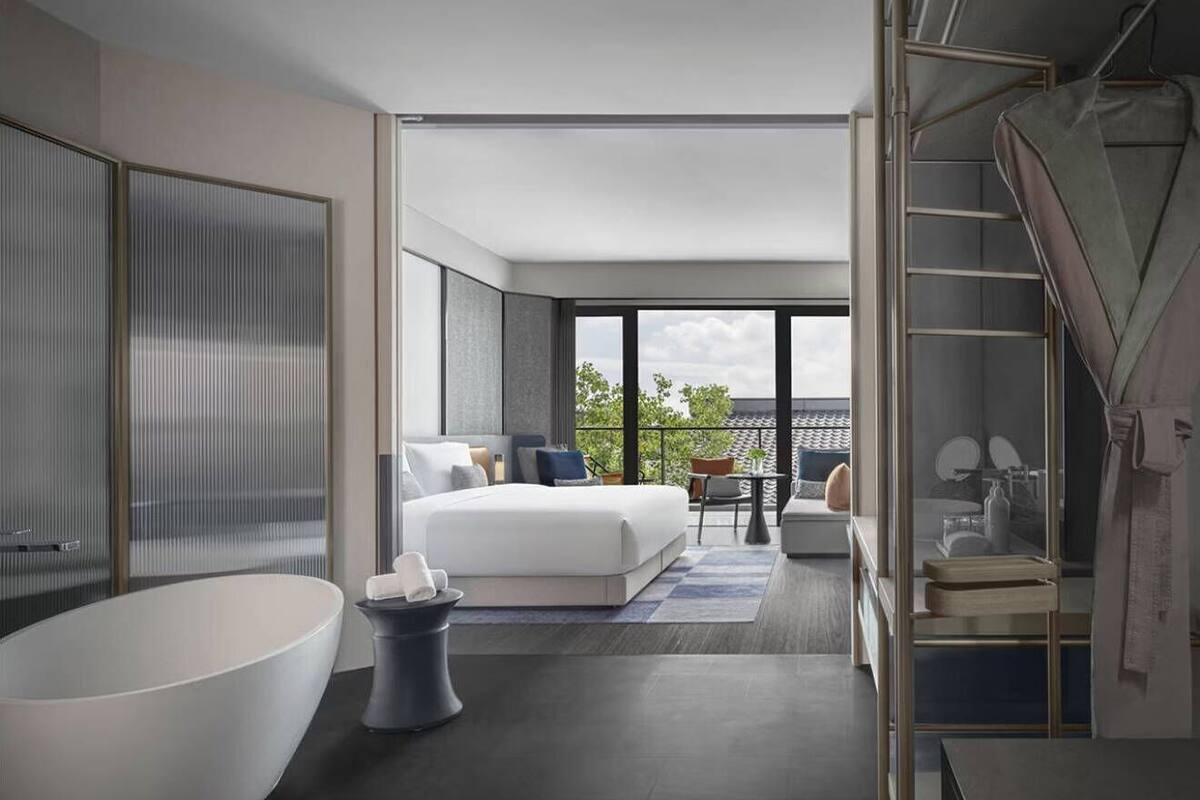 Ein modernes Hotelzimmer mit einem großen Bett, einer Badewanne, einem Balkon mit Blick und einer Treppe.