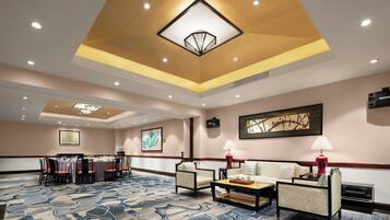 A hotel lobby with a conference table, seating area, and artwork on the walls.