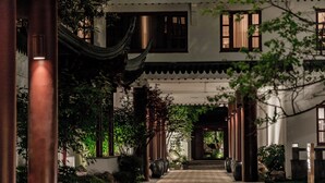 A traditional building with a covered walkway, columns, and potted plants. - Pan Pacific Suzhou (Suzhou)