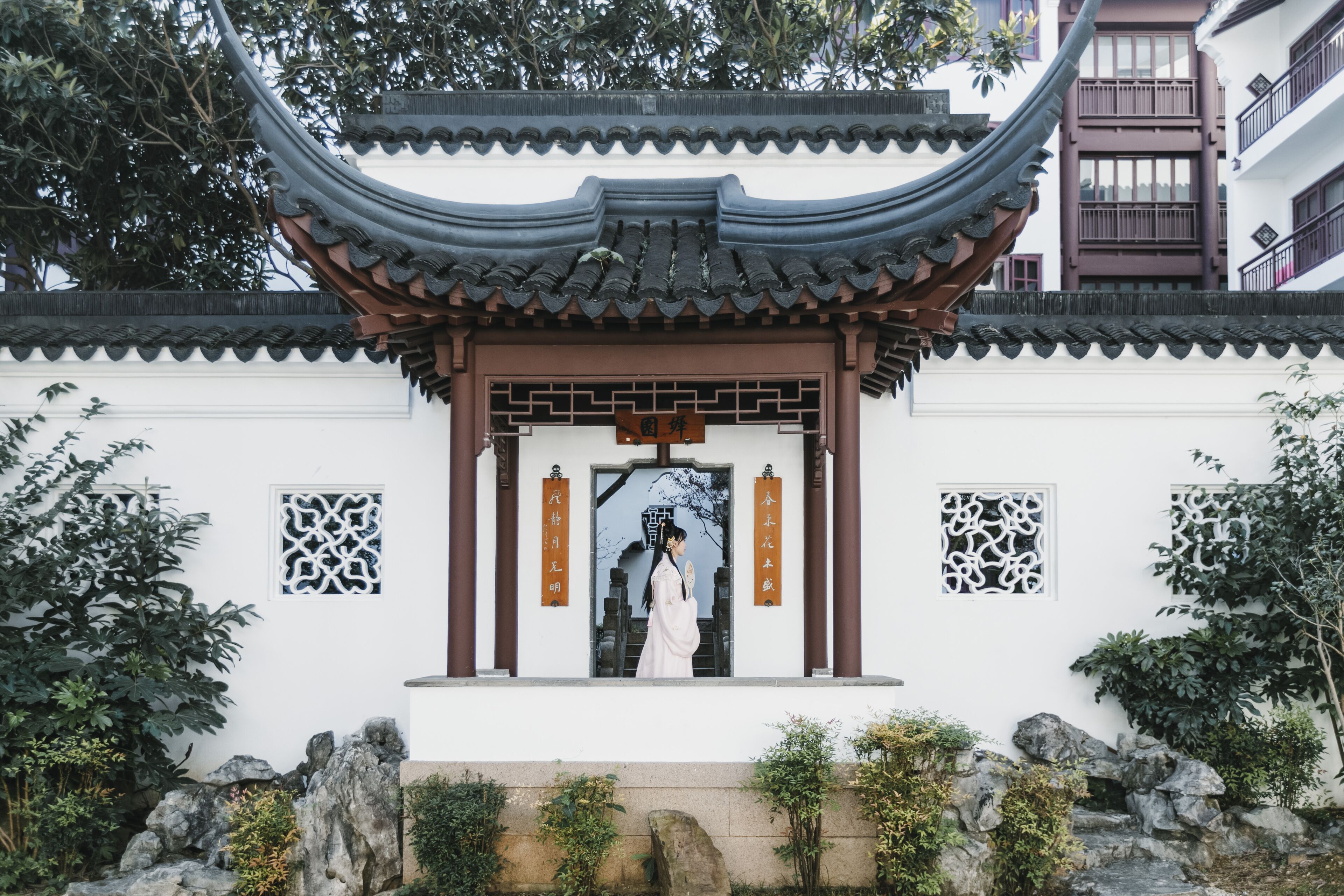 A traditional Chinese building with a curved roof, a central entrance, and decorative panels.