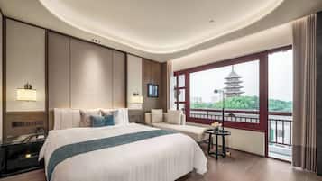 Une chambre d’hôtel avec un grand lit, une table de chevet, une télévision et une fenêtre donnant sur une pagode.