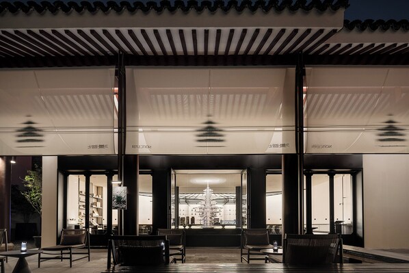 A modern building with a covered entrance, large windows, and a central chandelier. - Pan Pacific Suzhou (Suzhou)