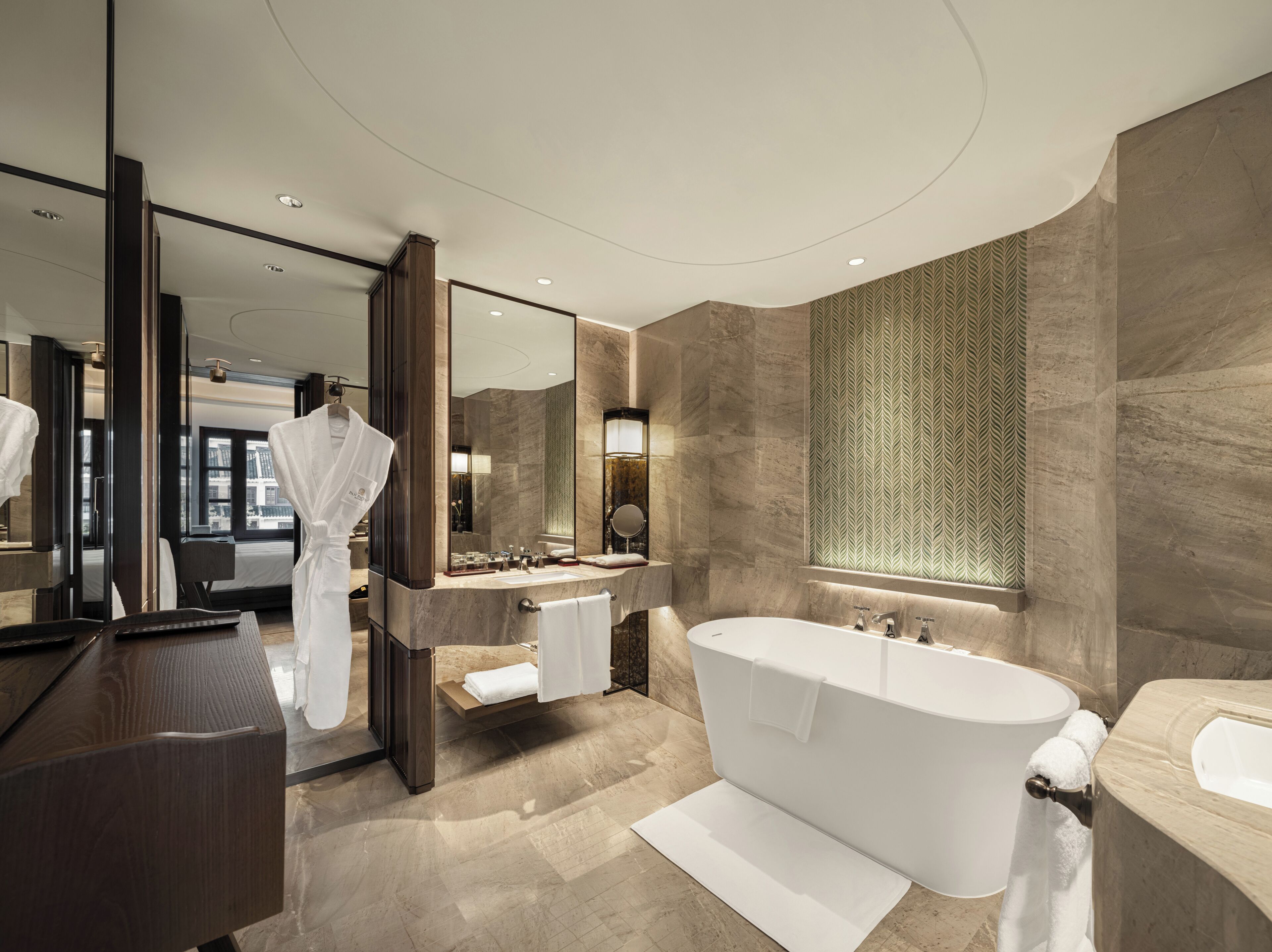 A modern bathroom with a large bathtub, a vanity with a mirror, and a large mirror above the sink.