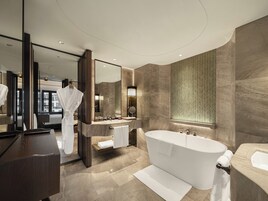 A modern bathroom with a large bathtub, a vanity with a mirror, and a large mirror above the sink.