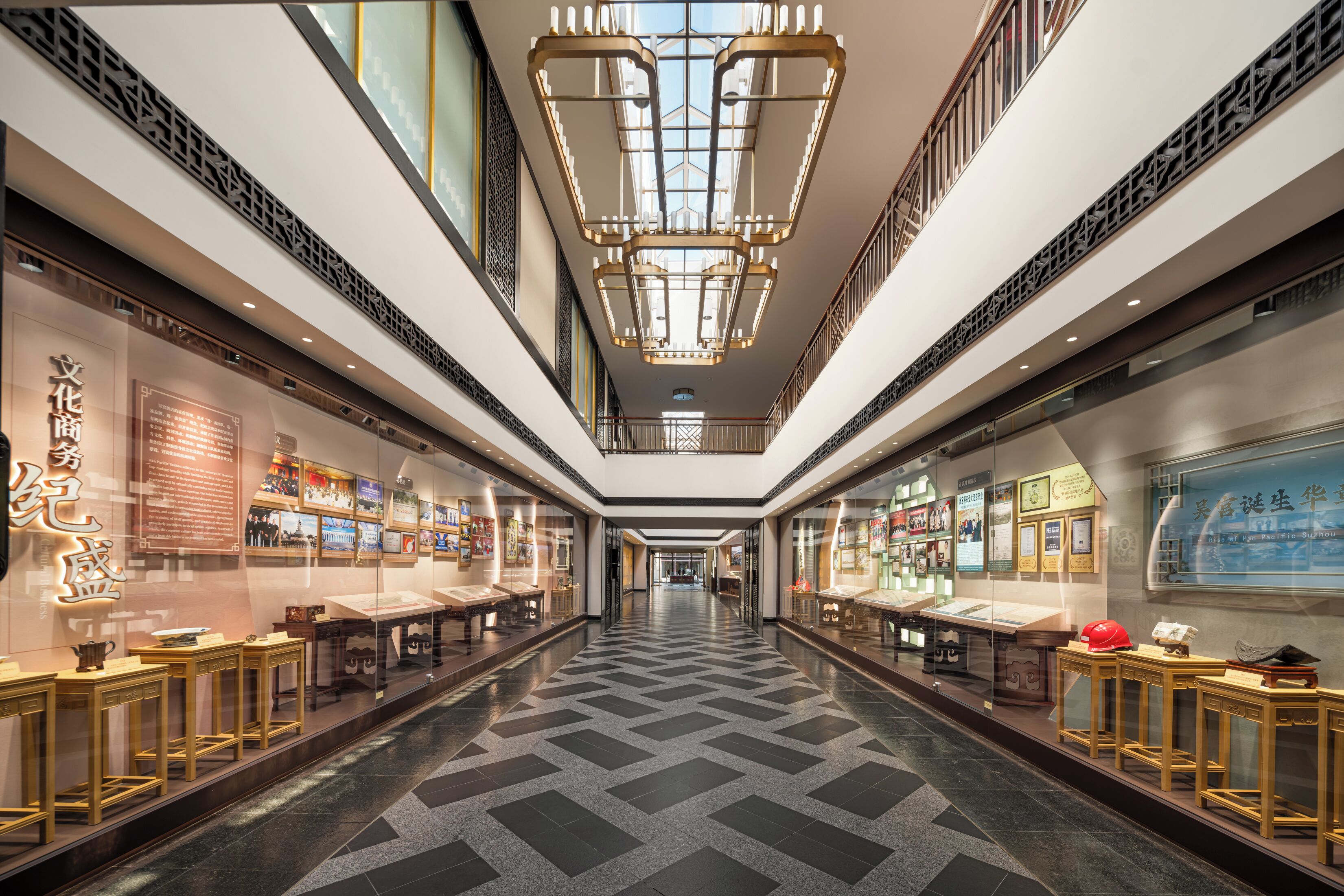 A corridor with a patterned floor, glass display cases, and a central chandelier.
