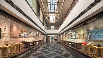 A corridor with a patterned floor, glass display cases, and a central chandelier.