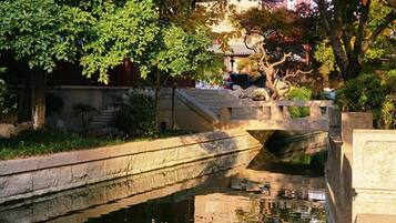 A serene waterway with a stone bridge, surrounded by lush greenery and autumn foliage.