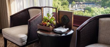 A balcony with two wicker chairs, a small table with a fruit basket, a folded napkin, and a decorative wooden plaque.