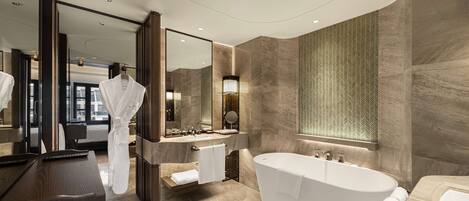 A modern bathroom with a freestanding bathtub, a large mirror, and a vanity with a sink.