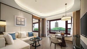 A modern hotel room with a sofa, a round table, a TV, and a view of a pagoda through large windows. - Pan Pacific Suzhou (Suzhou)