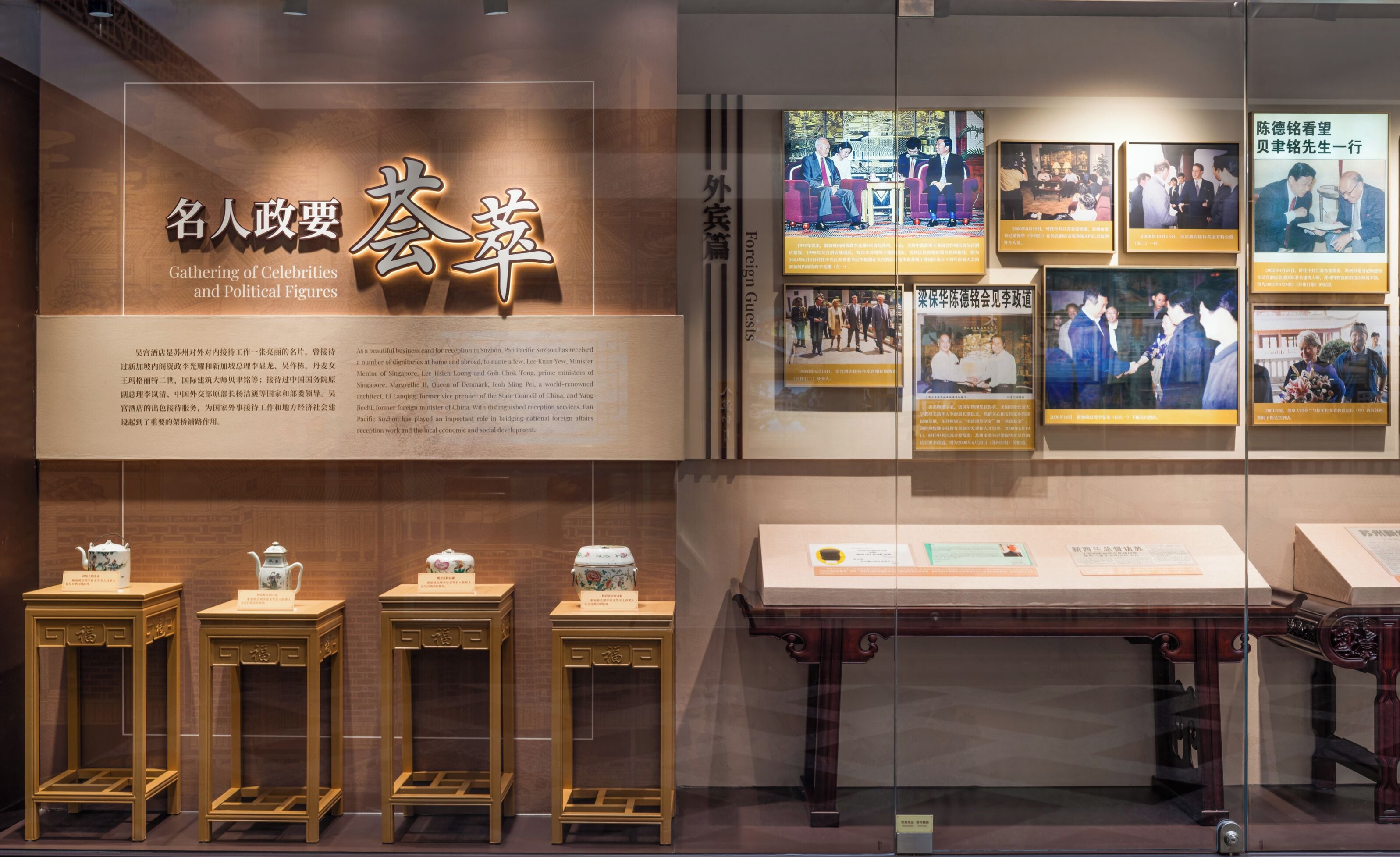 A museum exhibit with a sign reading "Gathering of Celebrities and Political Figures" and several framed photographs on the wall.