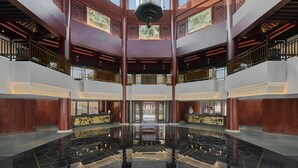 A spacious lobby with a high ceiling, large windows, and a central reflective floor. - Pan Pacific Suzhou (Suzhou)