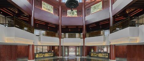 A spacious lobby with a high ceiling, large windows, and a central reflective floor.