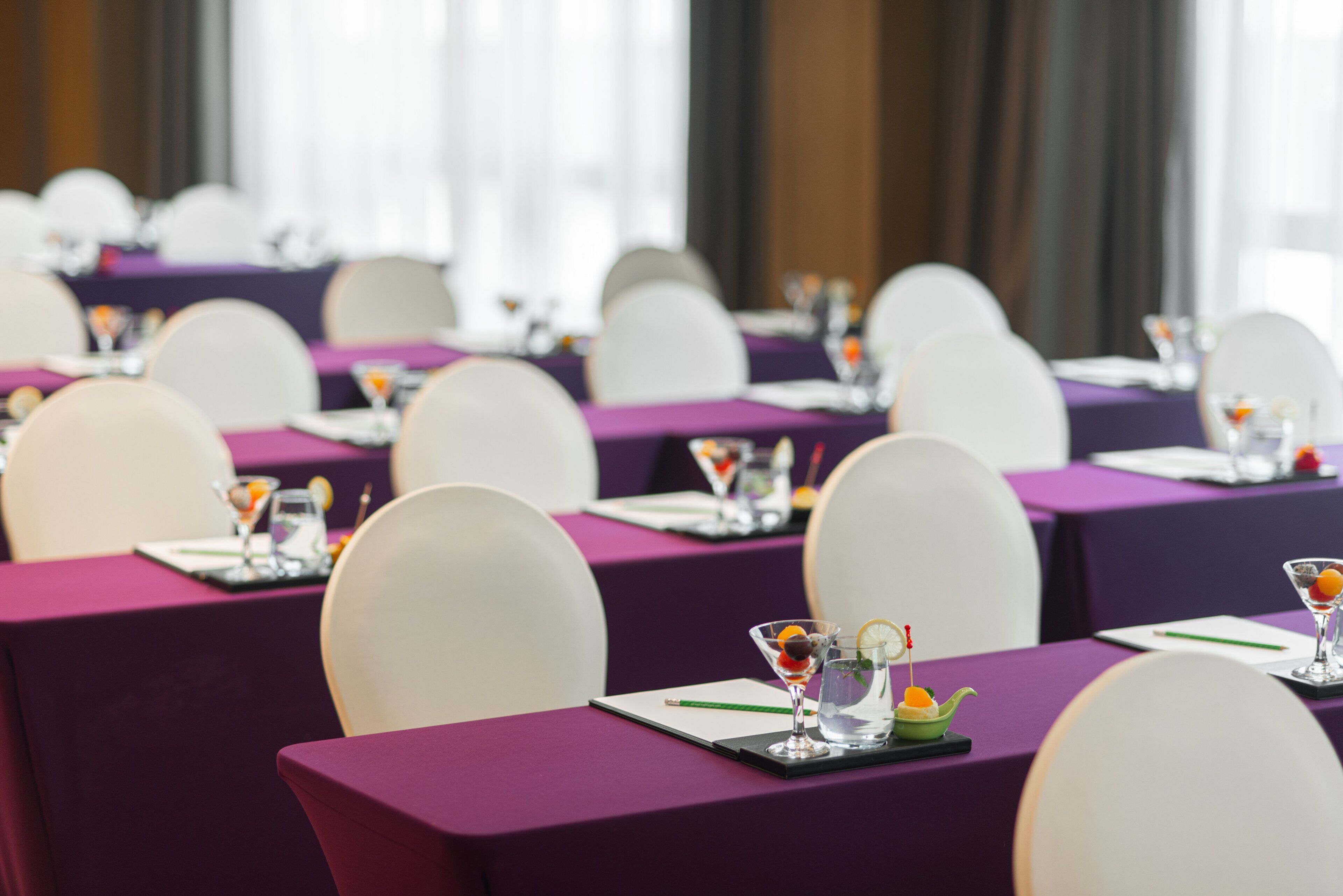 A conference room with purple tablecloths and white chairs.