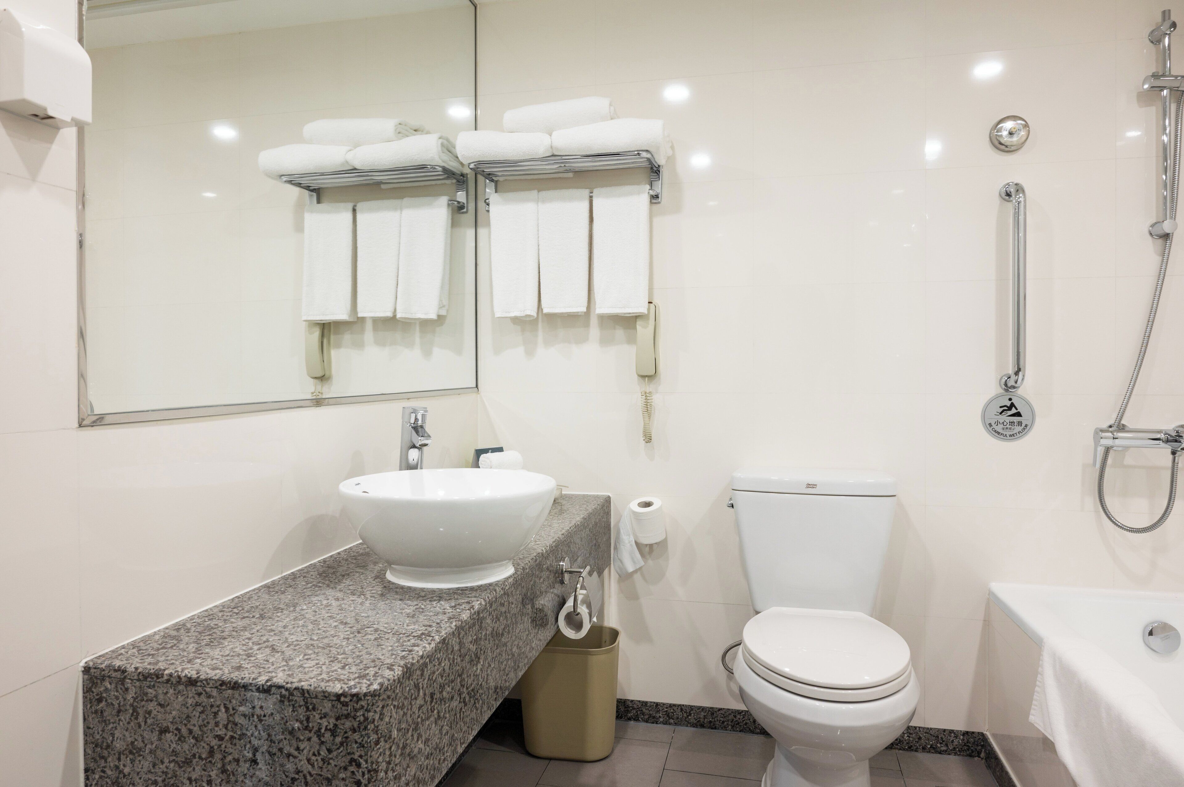 A modern bathroom with a granite countertop sink, a toilet, a bidet, and a bathtub.