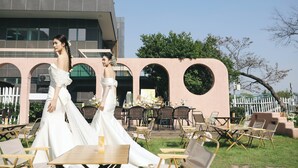An outdoor wedding venue with a modern building, tables, and chairs arranged for guests.