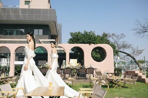 An outdoor wedding venue with a modern building, tables, and chairs arranged for guests.
