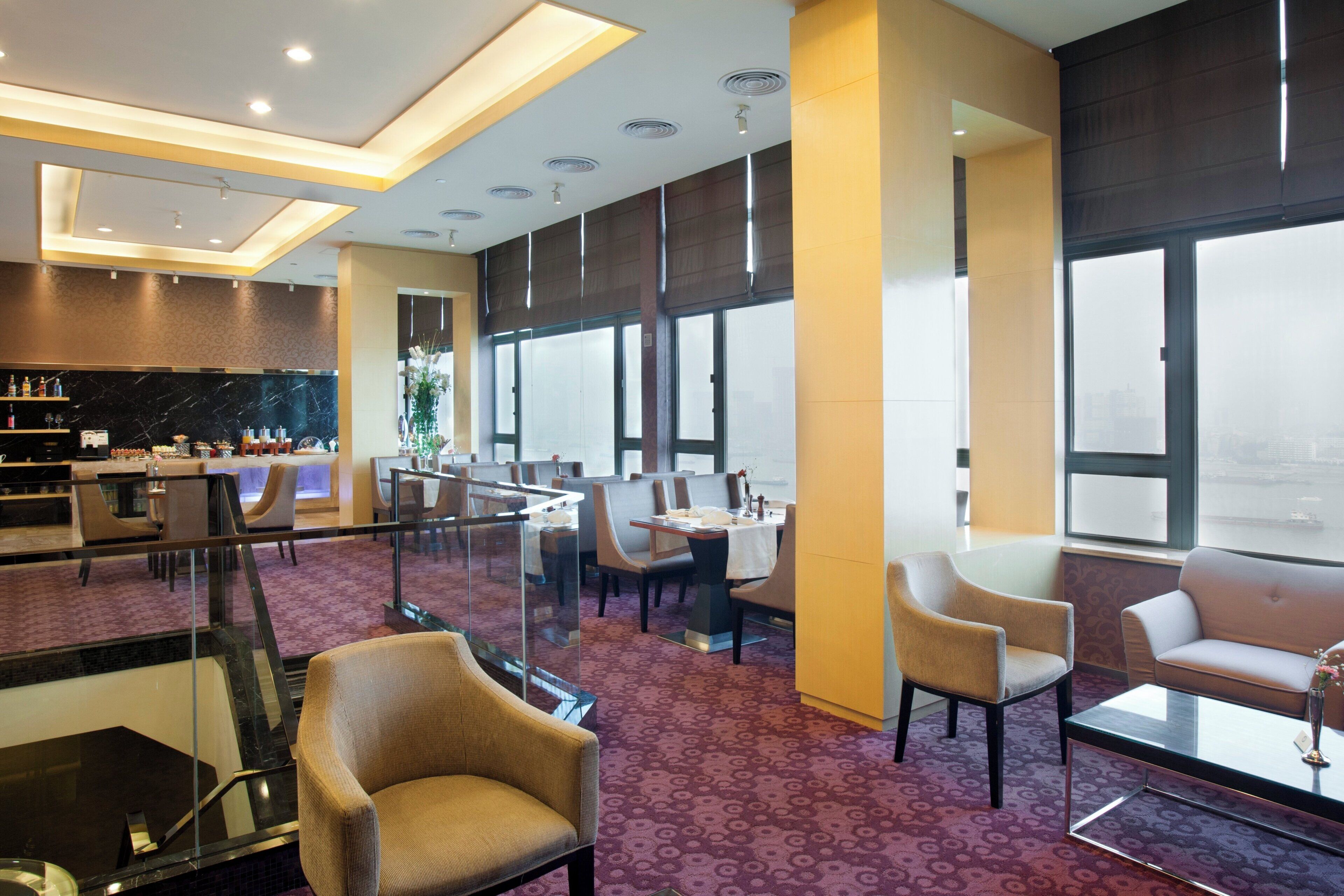 A hotel lobby with a reception desk, seating area, and a bar.