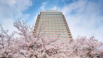Stunning hotel building with a modern design, surrounded by blooming cherry blossom trees.