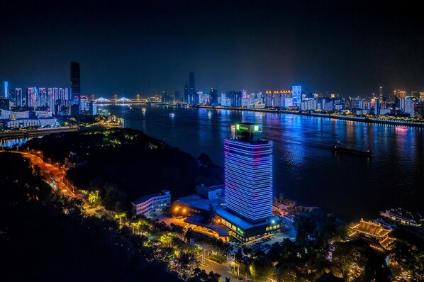 A nighttime cityscape with illuminated buildings and a river.