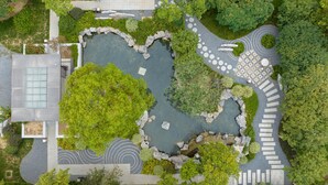 An aerial view of a landscaped area with a central pond, stone pathways, and surrounding greenery. - Holiday Inn Express Zhengzhou by IHG (Zhengzhou)