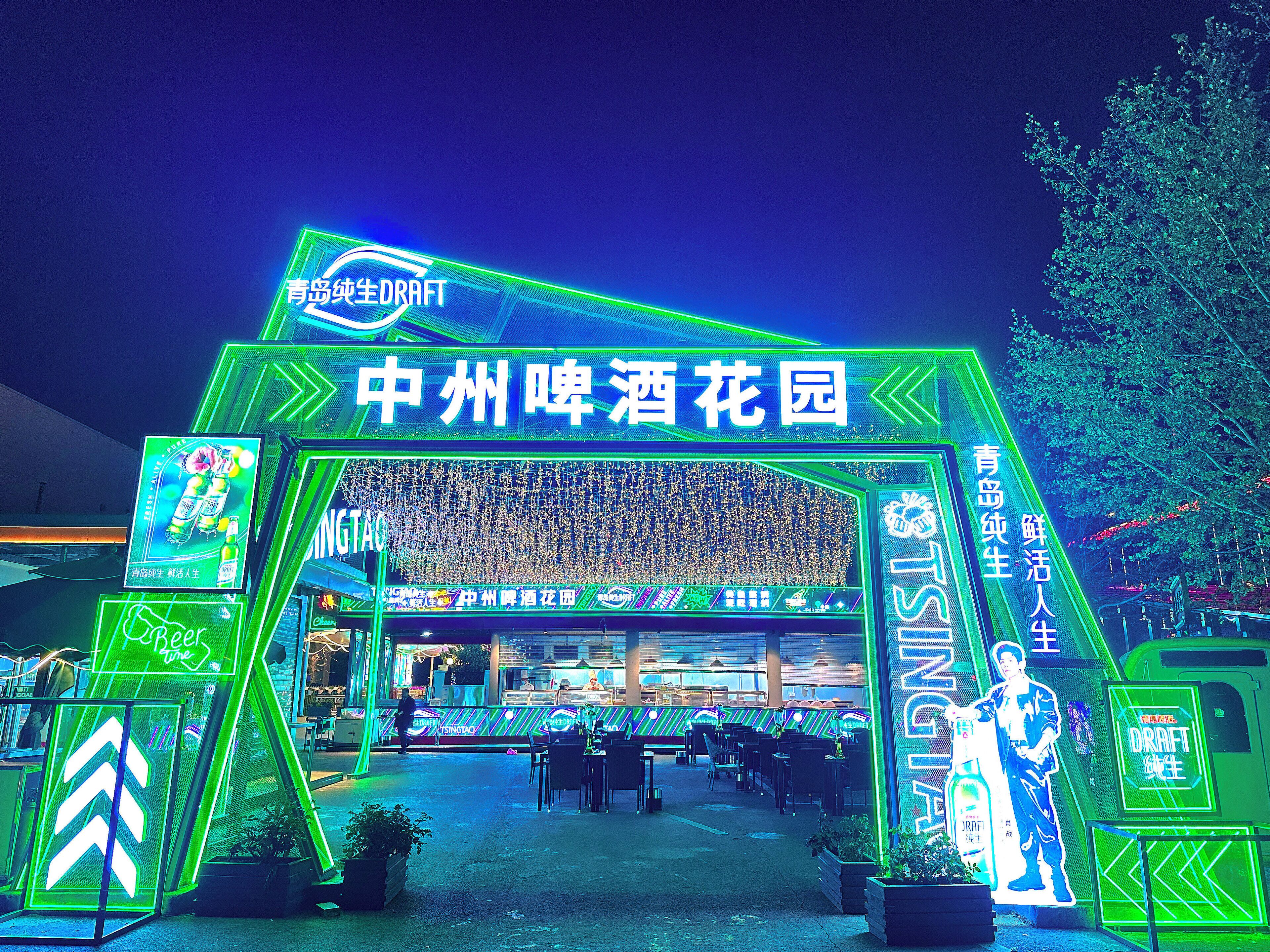 An outdoor area with neon signs and a seating area, likely part of a public space or event venue.