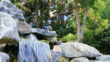 A waterfall cascading over rocks in a natural setting with trees in the background.