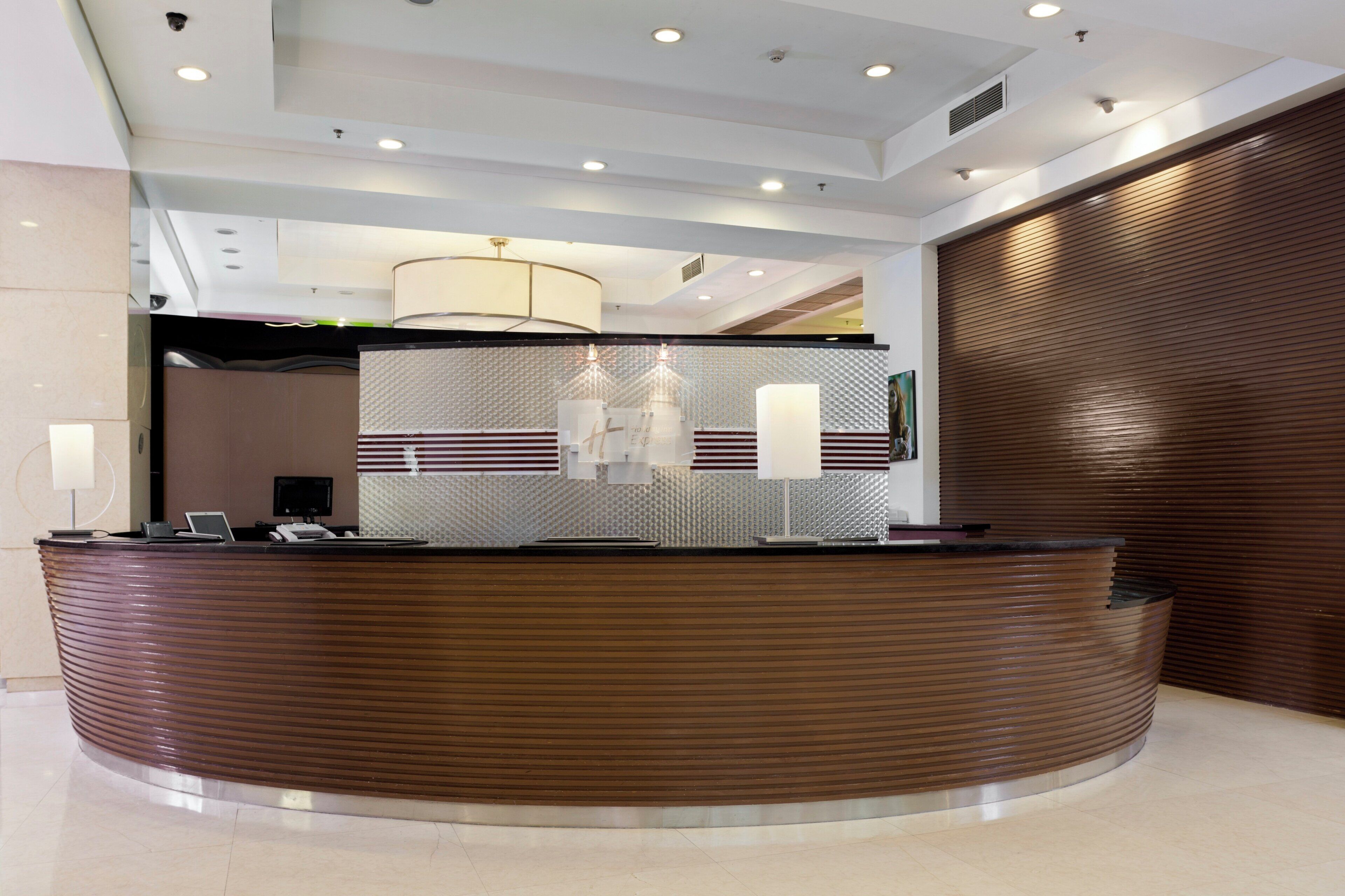A reception desk with a modern design, a chandelier, and a patterned wall in the background.