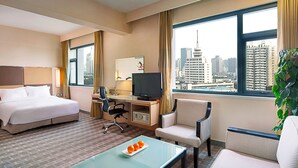 A hotel room with a bed, desk, chair, TV, and a view of the cityscape. - Holiday Inn Express Zhengzhou by IHG (Zhengzhou)