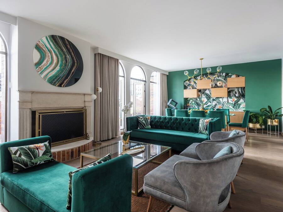 Una sala de estar moderna con chimenea, sofás verdes y un cuadro abstracto grande.
