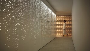 A hallway with a patterned wall and a person walking.