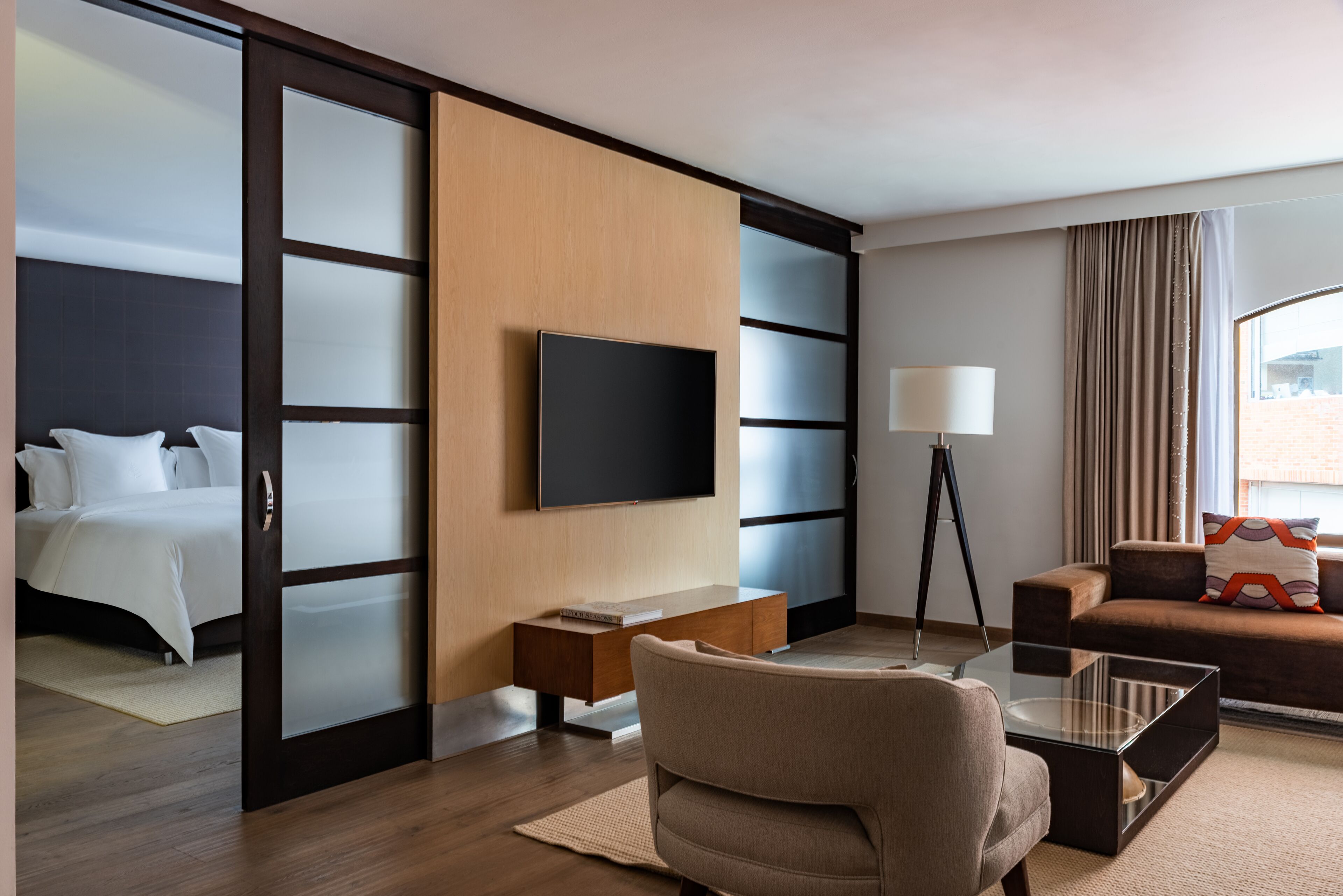 Una camera d'albergo con un letto, un divano, una televisione, una scrivania e una lampada.