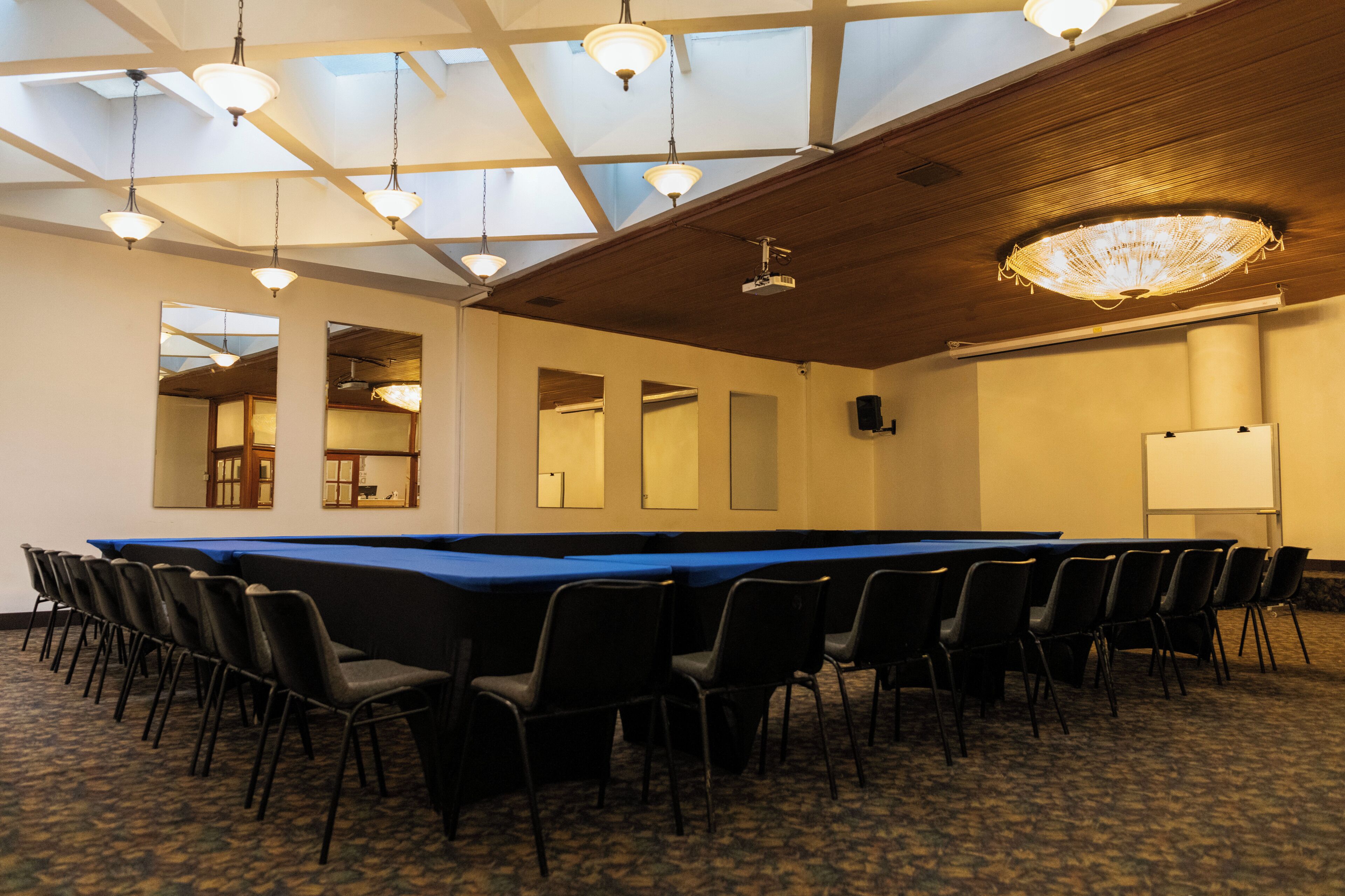 A conference room with a long table, chairs, a chandelier, and a whiteboard.