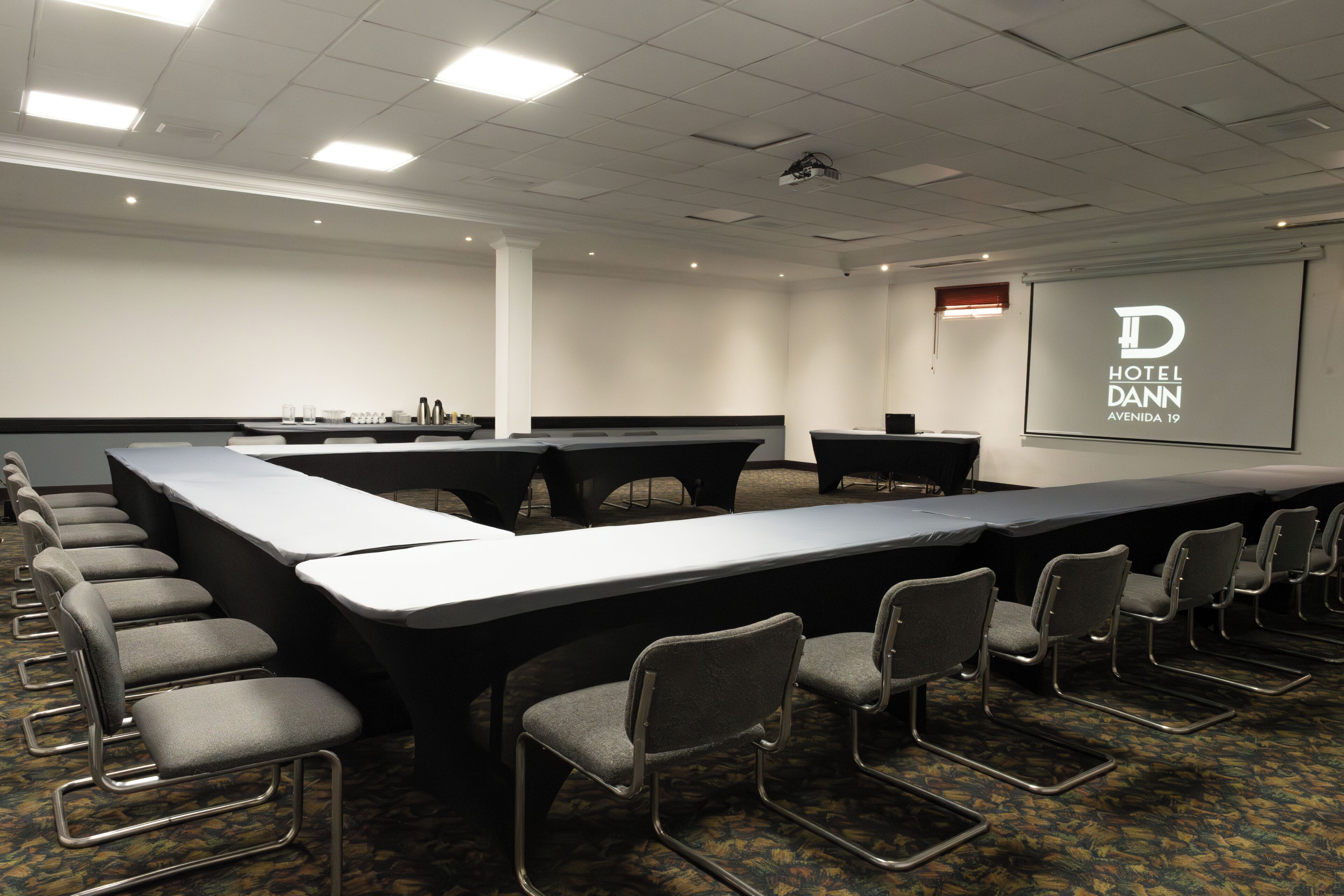 A conference room with a long table, chairs, a projector screen, and a whiteboard.