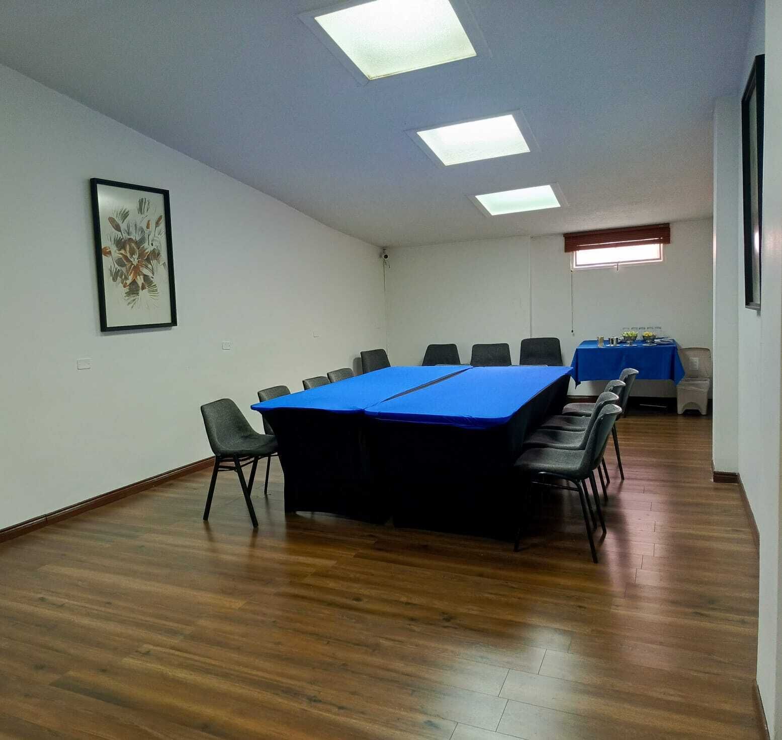 A conference room with a long table, chairs, and a framed picture on the wall.