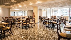 Un comedor espacioso con varias mesas y sillas, piso de granito pulido y un diseño de techo moderno.