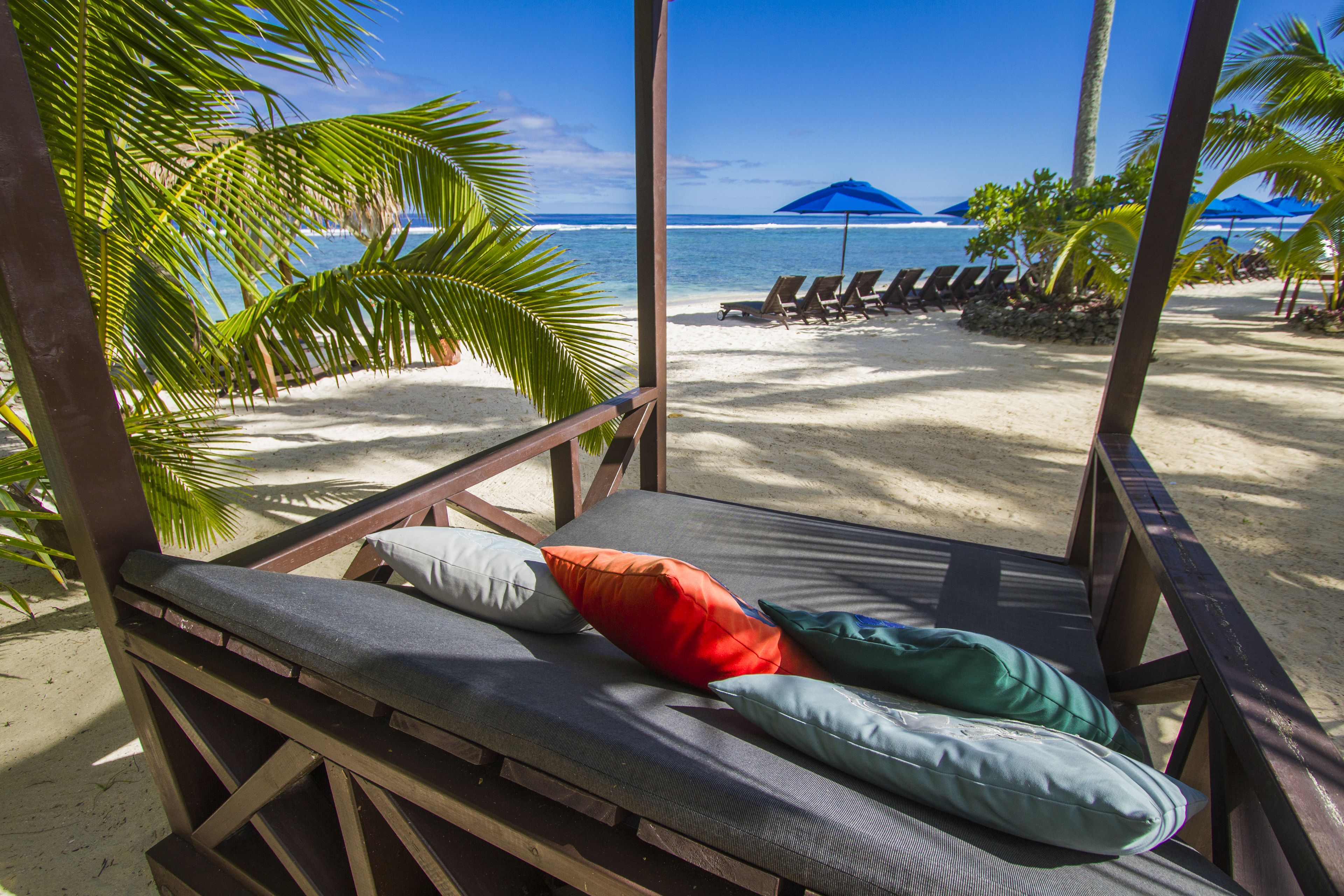 A beach view with a wooden bench and lounge chairs.