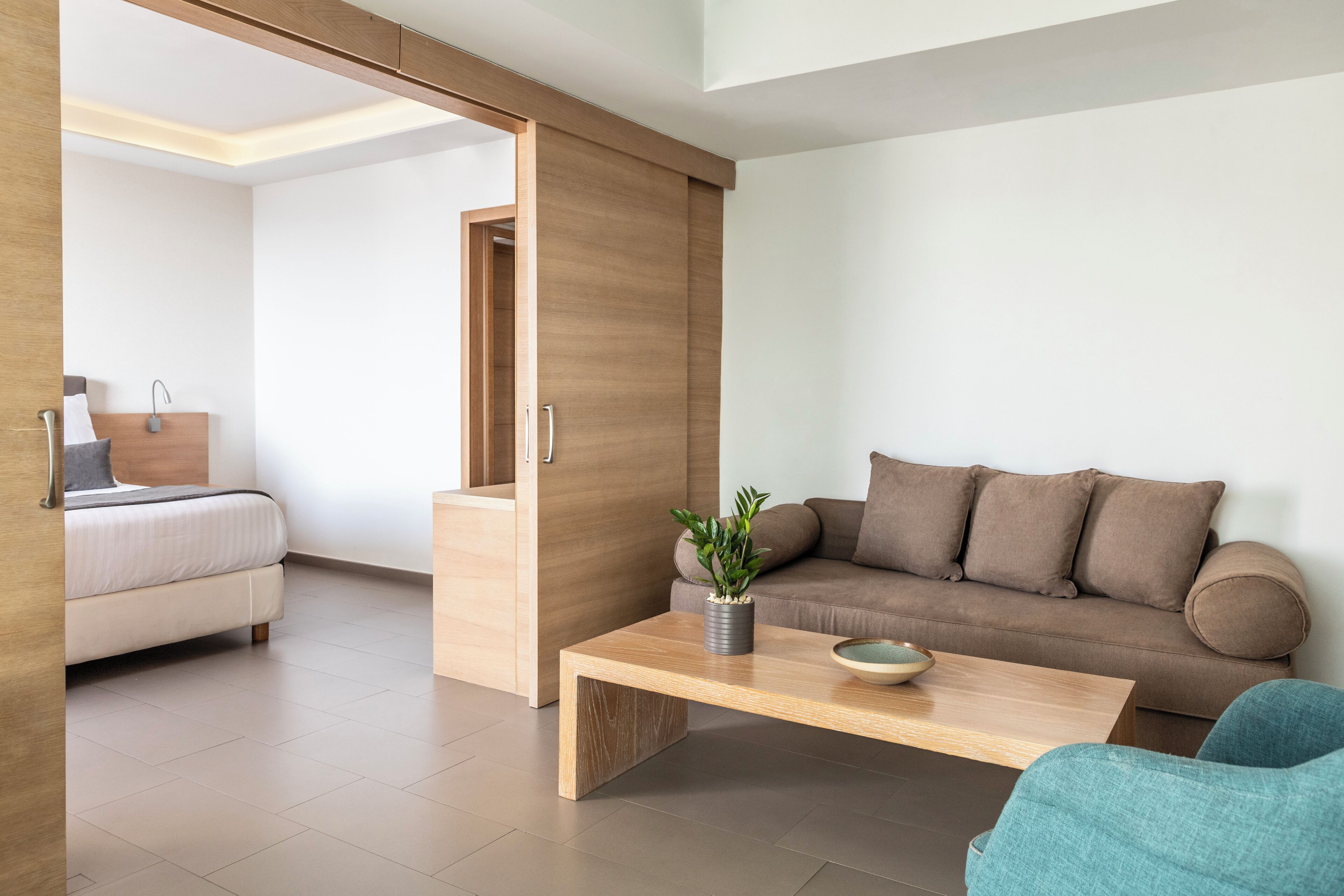Een moderne woonkamer met een bank, een bijzettafeltje en een blauwe fauteuil.