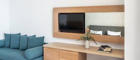 Una habitación moderna con sofá, un escritorio de madera, un espejo y una planta pequeña.