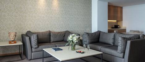 A modern living room with a grey sectional sofa, a coffee table, and a bust on a side table.