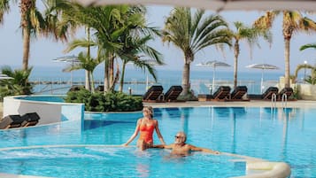 Una piscina techada, una piscina al aire libre, sombrillas