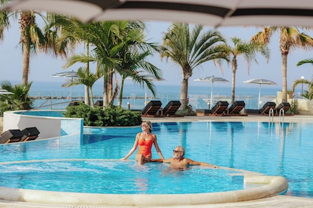 Una piscina techada, una piscina al aire libre, sombrillas