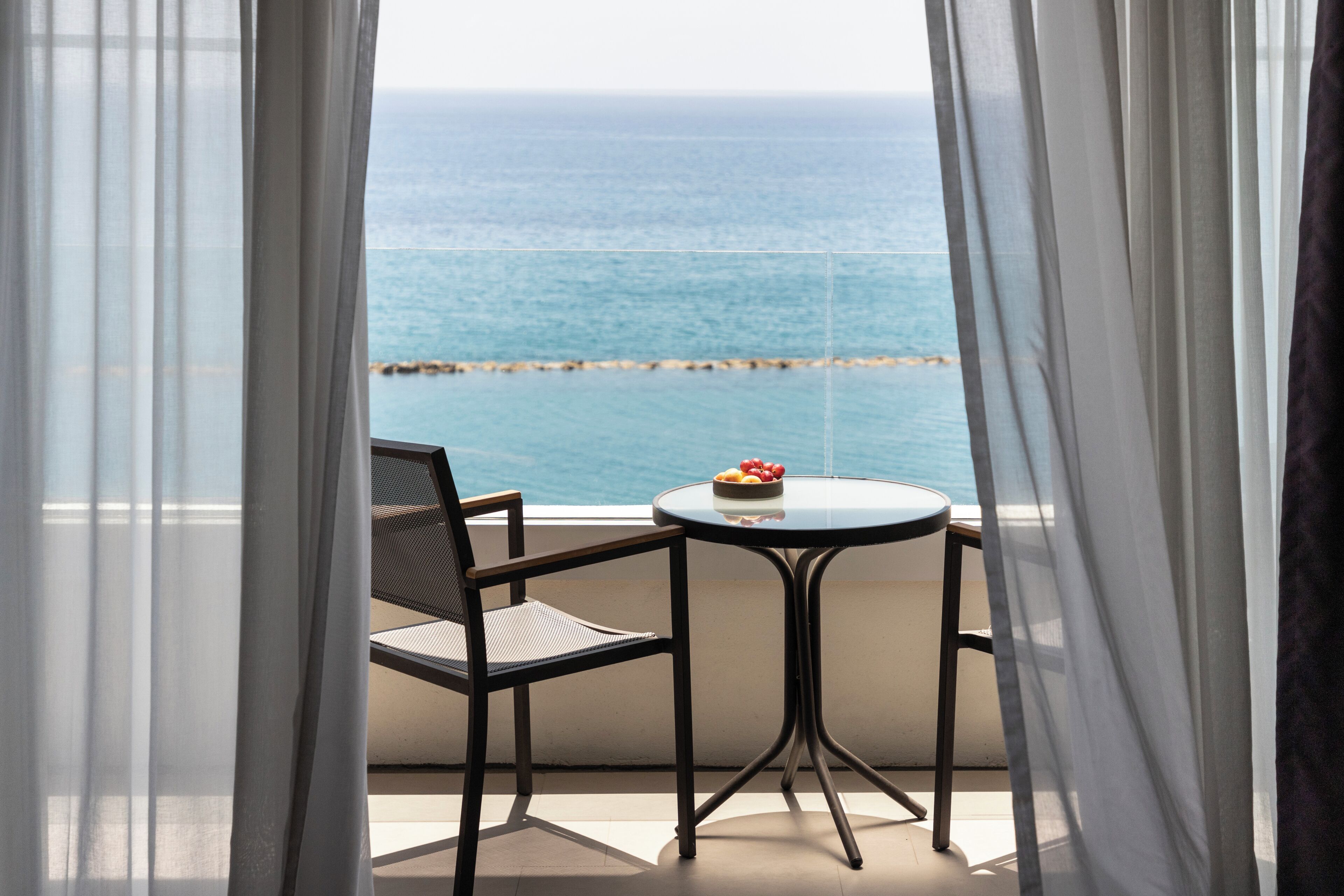 Un balcón con una mesa y una silla, con vistas al mar.