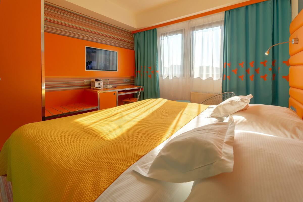 Una habitación de hotel con cama, escritorio, silla y televisor.