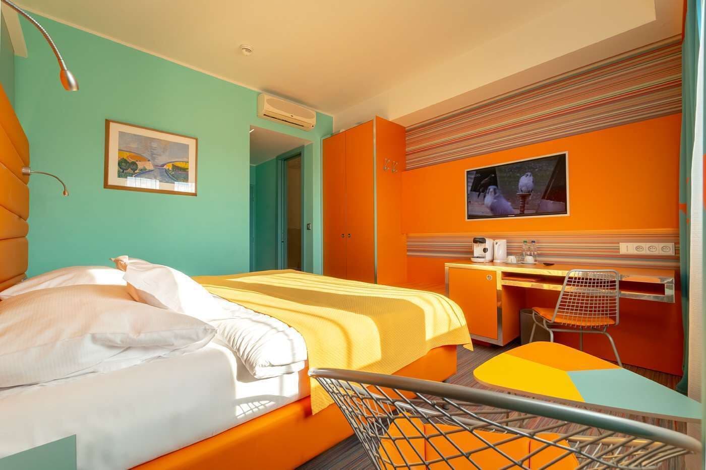 A hotel room with a bed, a desk, a television, and a chair.