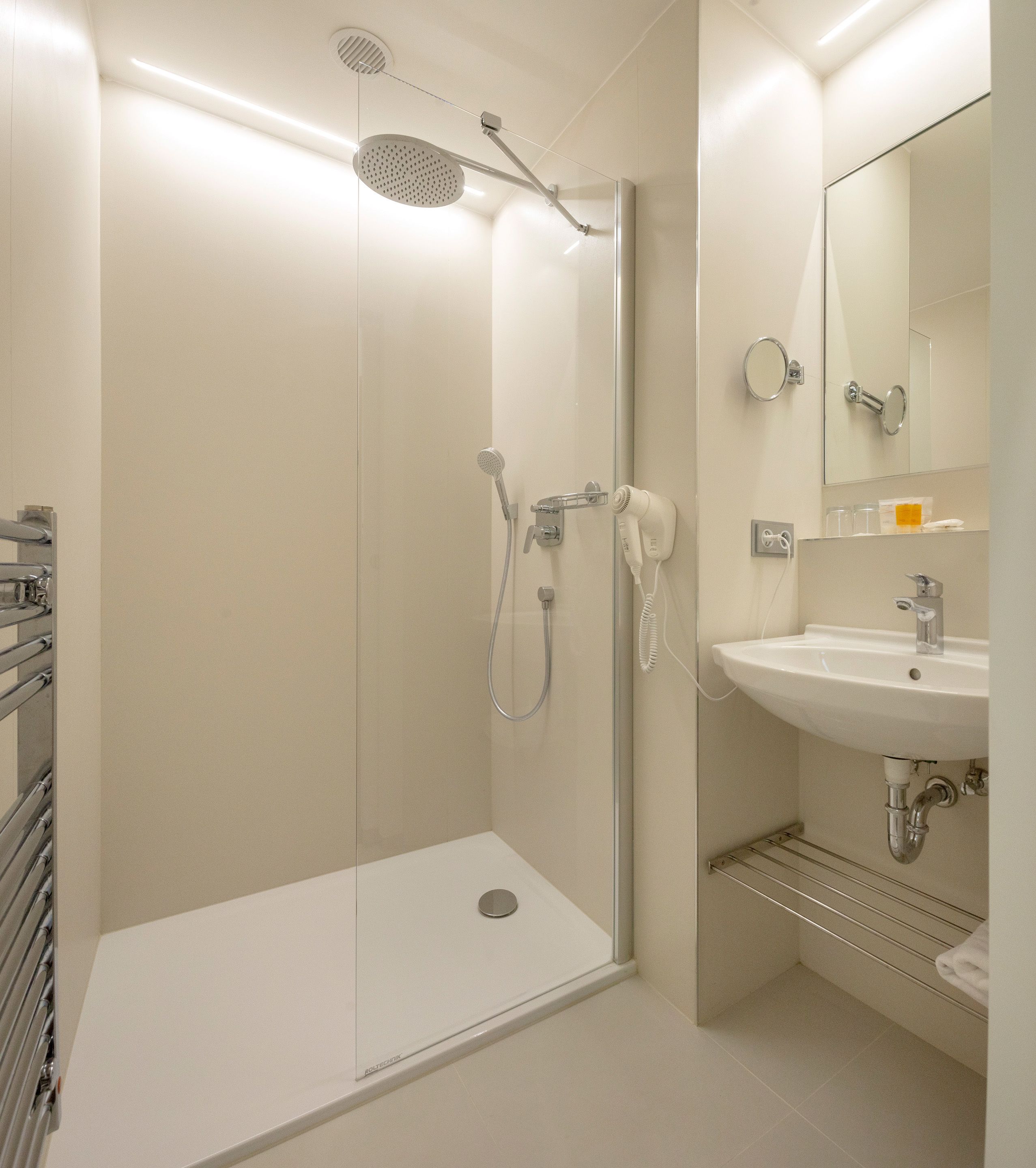 Un baño moderno con cabina de ducha de vidrio, un lavabo y un espejo.