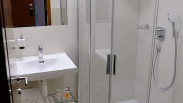 A modern bathroom with a glass-enclosed shower, a white sink, and a toilet.