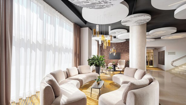 A modern lobby with a curved sofa, a coffee table, and a potted plant. - Imperial Hotel Ostrava (Ostrava)