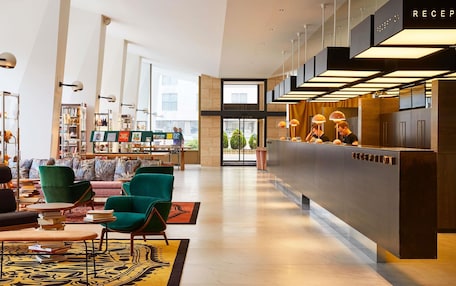 A modern lobby with a reception desk, seating area with sofas and chairs, and a large window providing a view of the outside.